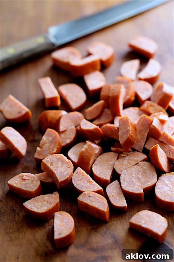 Andouille sausage cut into pieces on wooden cutting board