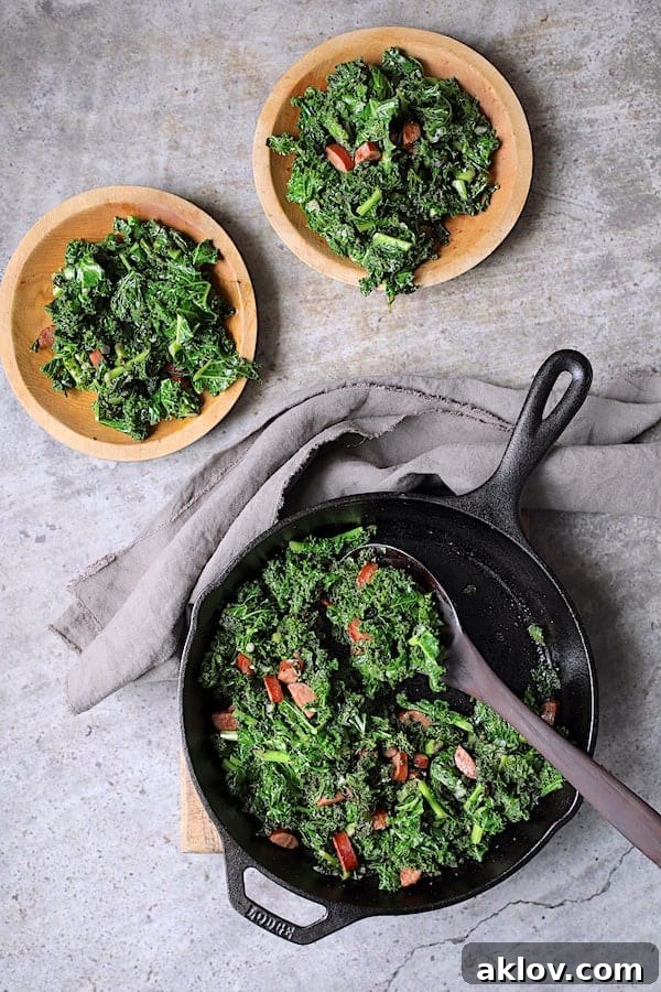 Spicy Sautéed Kale with Andouille Sausage - Overhead shot of dish being served from cast iron skillet onto wooden plates