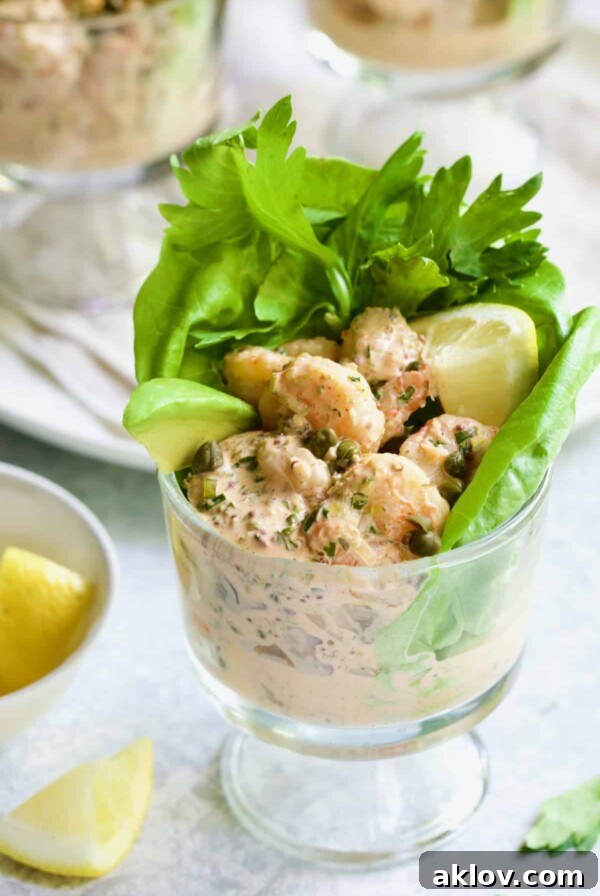 Photo of Sriracha Shrimp Remoulade Cocktail with lettuce, celery leaves, avocado wedge and lemon wedge.