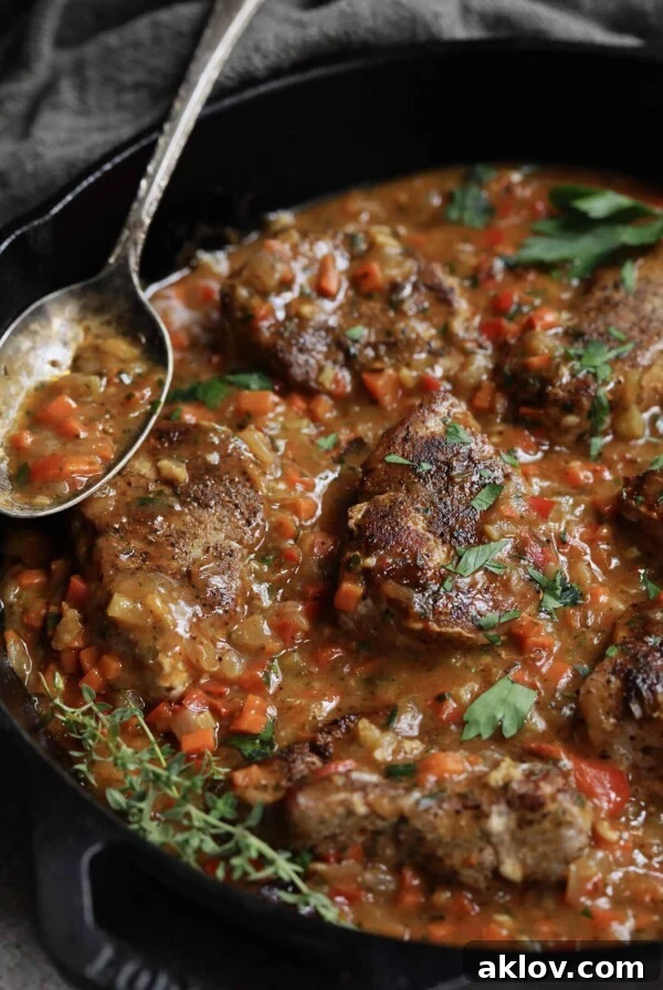 Cajun-Smothered Pork Medallions - Close-up shot in cast iron skillet with thyme sprigs