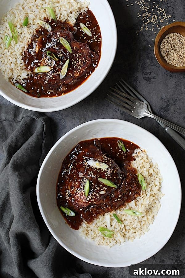 Photo of Korean Braised Chicken Thighs in white bowls with rice garnished with scallion and sesame seeds, illustrating a vibrant, ready-to-serve dish.