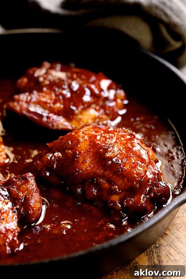 Photo of Korean Braised Chicken Thighs simmering in a cast-iron skillet, immersed in the rich sauce.