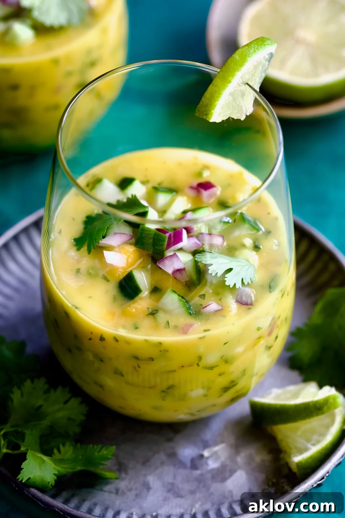 Mango Gazpacho on metal tray garnished with cilantro and lime wedges.