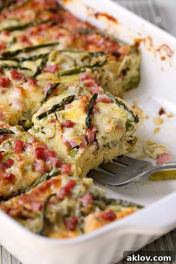 Close-up view of a serving of Breakfast Strata being lifted from the baking dish, showing its layered texture and golden crust.