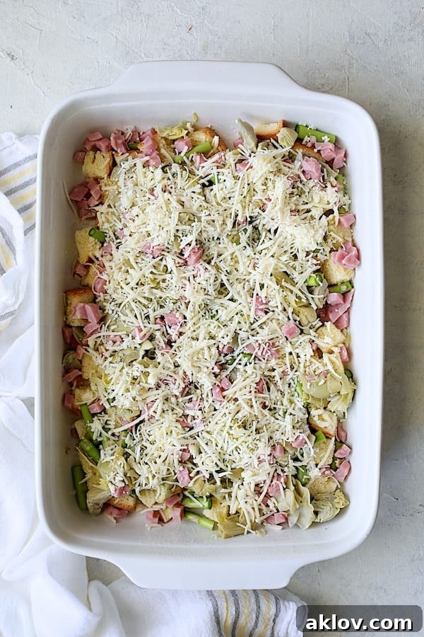 The first layer of brioche, asparagus, artichokes, and ham, generously topped with grated Gruyere cheese.