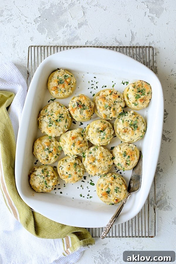 The baked Lemon Parmesan Stuffed Artichoke Bottoms, golden and bubbling, resting in their white baking dish on a cooling rack.