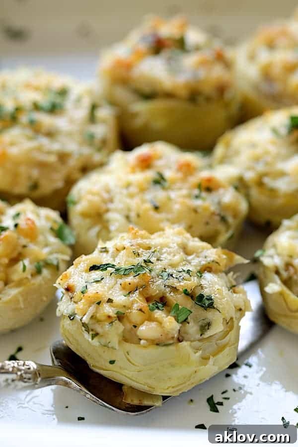 A close-up view of a baked Lemon Parmesan Stuffed Artichoke Bottom being carefully lifted from the baking dish with a serving utensil.