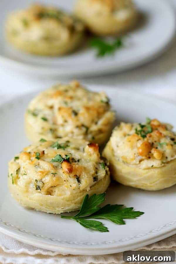 Close-up of three Lemon Parmesan Stuffed Artichoke Bottoms on a white plate, showcasing the golden, bubbly filling.