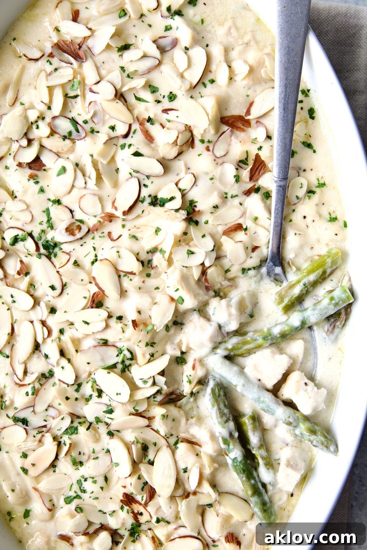 A generous serving of Chicken Divan with Asparagus, garnished with sliced almonds, scooped onto a plate, showcasing its creamy texture.
