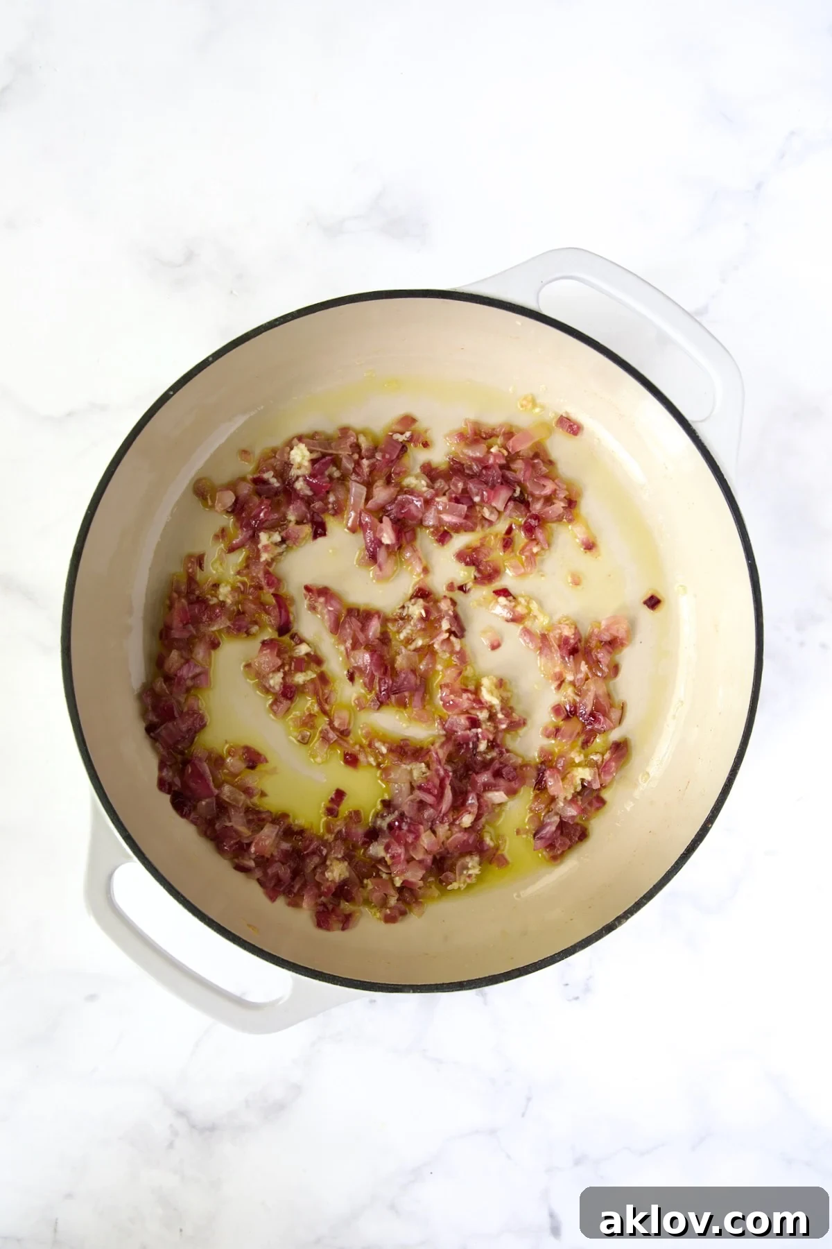Cooked red onion in white enamel cast iron skillet.