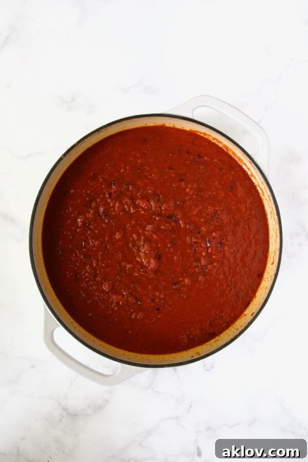 Marinara and crushed tomatoes added to white enamel cast iron skillet.