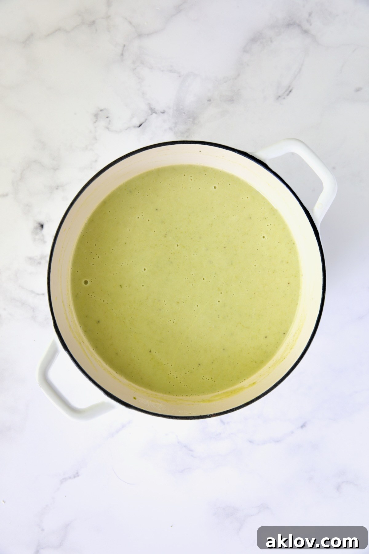 Creamy Celery Leaf Soup after being pureed to a smooth consistency in a white Dutch oven.