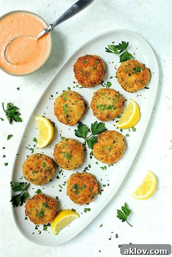 Nine shrimp cakes on an oval white platter garnished with lemon and parsley, showcasing the finished dish.