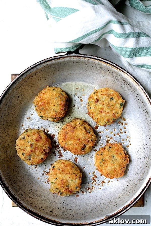 Golden Shrimp Cakes with Fire-Roasted Red Pepper Aioli 6 Several shrimp cakes sizzling and browning in a hot skillet, developing a golden crust.