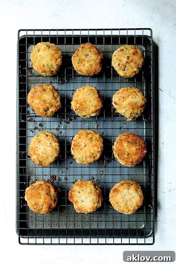 Golden Shrimp Cakes with Fire-Roasted Red Pepper Aioli 7 Twelve freshly fried shrimp cakes neatly arranged on a cooling rack, placed over a baking sheet to properly drain excess oil.