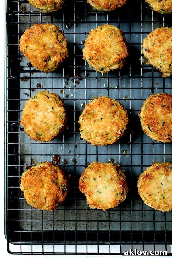 Golden Shrimp Cakes with Fire-Roasted Red Pepper Aioli 8 A close-up shot of cooked shrimp cakes resting on a cooling rack set over a baking sheet, showing their readiness after oven baking.
