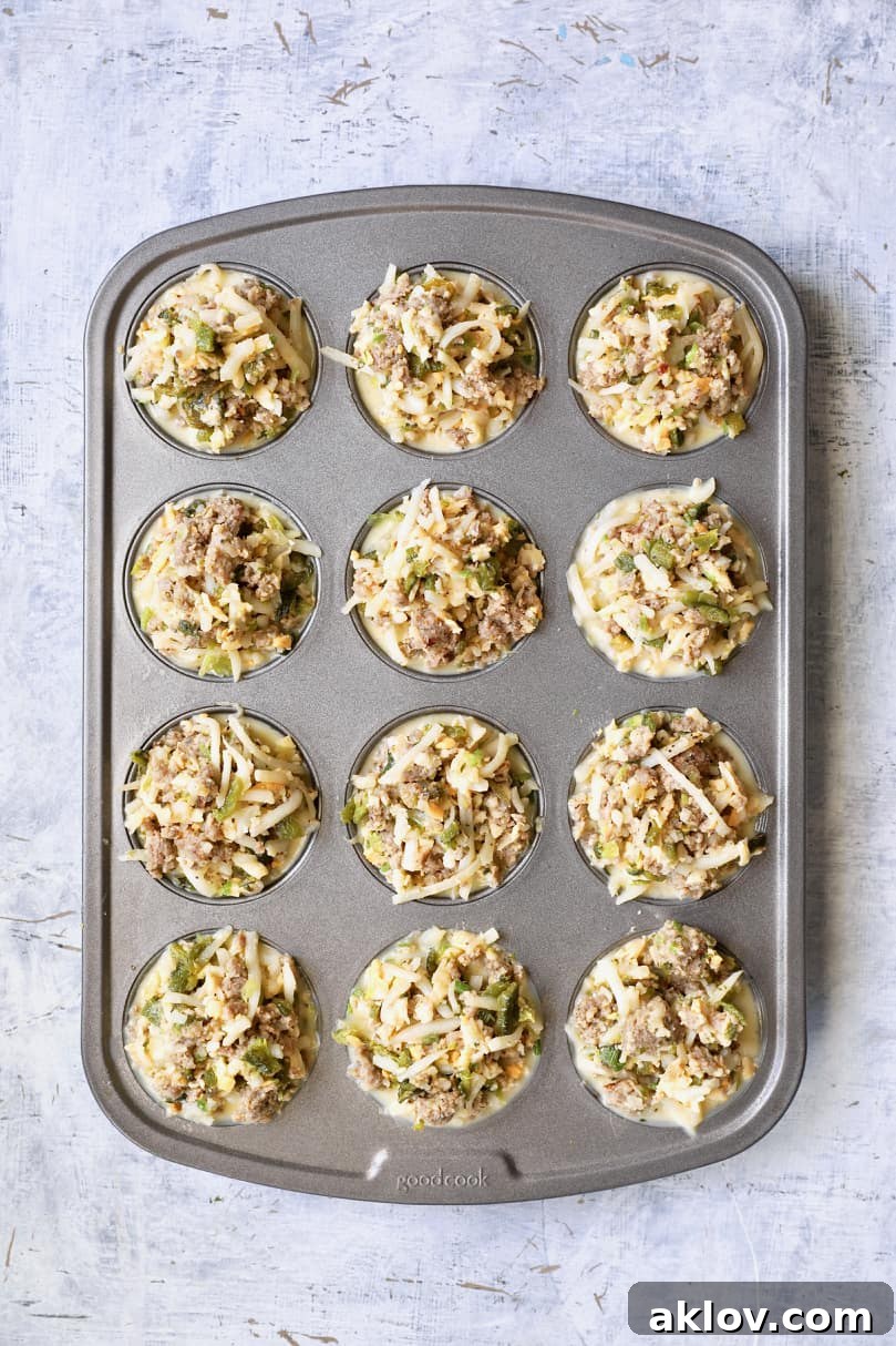 Photo of the hearty meat, potato, and cheese mixture being added to the muffin cups, which already contain the egg custard, prior to baking.