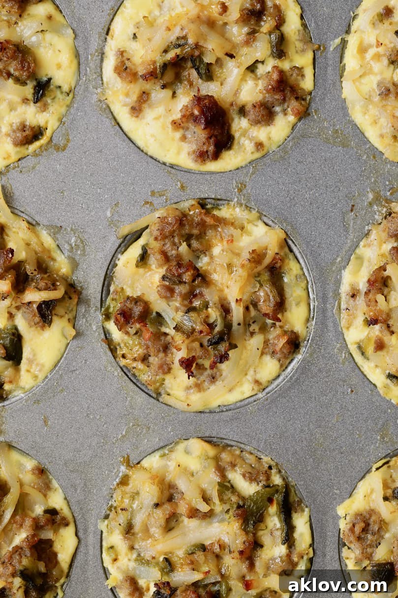 Overhead close-up photo of golden brown, savory breakfast muffins still nestled in the muffin pan, showing their perfectly baked tops.