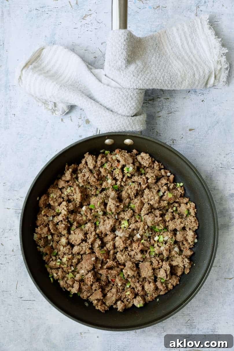 Close-up photo of savory sausage and vibrant green scallions, perfectly cooked together in a skillet.