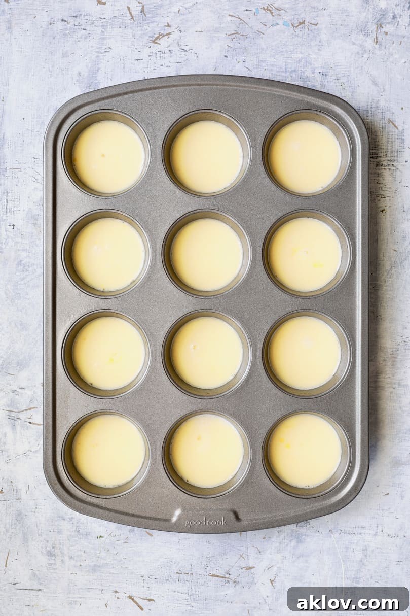 Close-up photo of the egg and milk mixture carefully poured into the cups of a muffin pan, ready for additional ingredients.