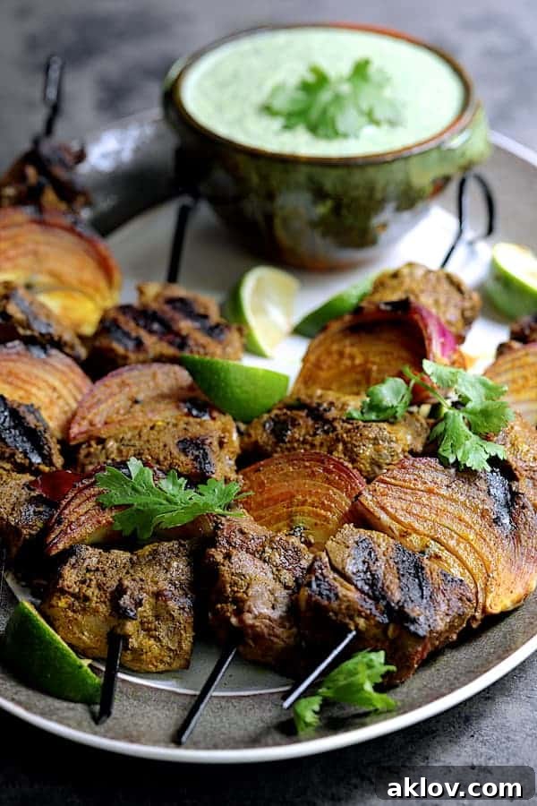 Indian-Style Beef Kabobs on skewers, ready for grilling, alongside fresh ingredients