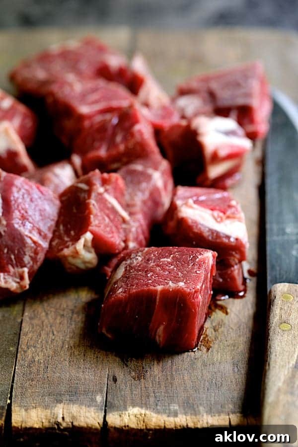 Cubed beef on a wooden cutting board, ready for marinade
