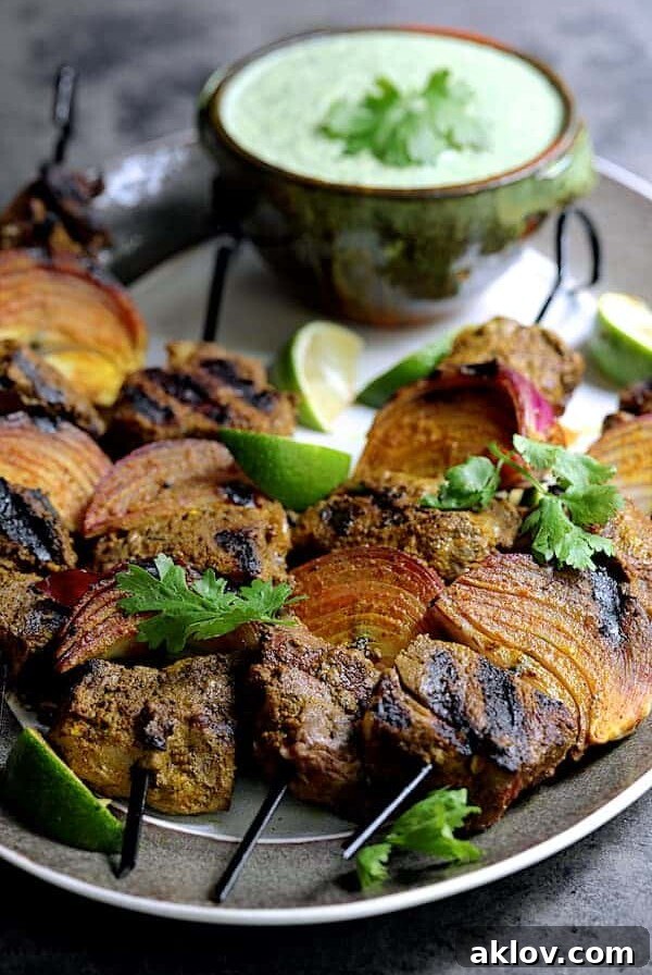 Four Indian-Style Beef Kabobs with Cilantro - Coconut Sauce on a gray-rimmed platter.