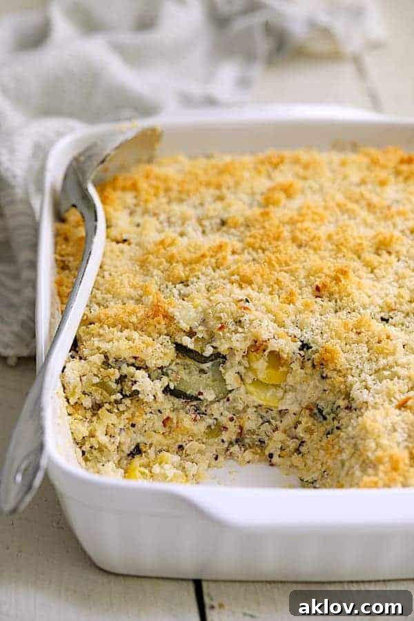 Creamy Zucchini, Yellow Squash and Quinoa Casserole in a white baking dish, with a portion served to reveal the rich, layered interior.