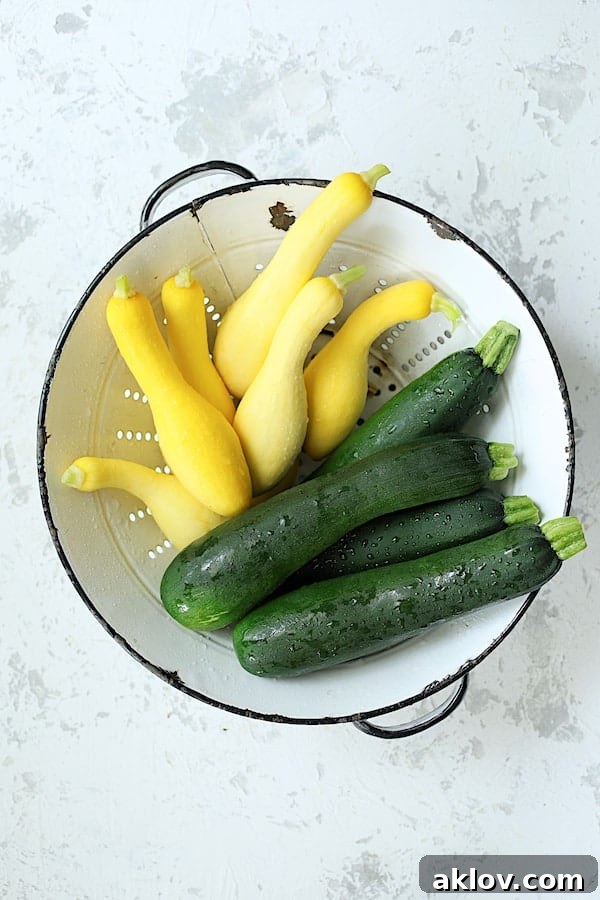Freshly picked zucchini and yellow squash in a white colander, ready for preparation for a healthy vegetarian casserole.