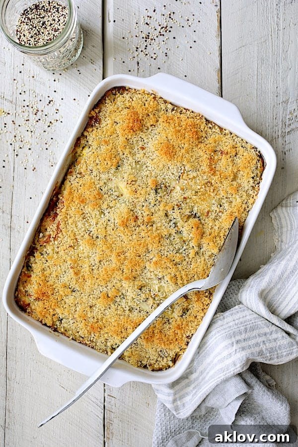 A freshly baked Zucchini, Yellow Squash and Quinoa Casserole, golden brown and bubbling, presented on a white wooden background, ready to be served.