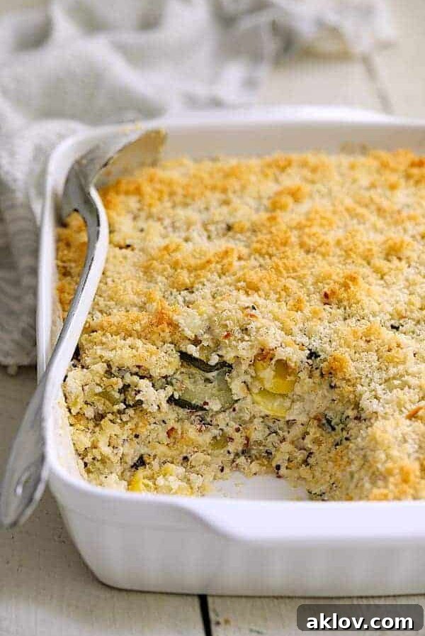 Zucchini, Yellow Squash and Quinoa Casserole in white baking dish with a serving removed.
