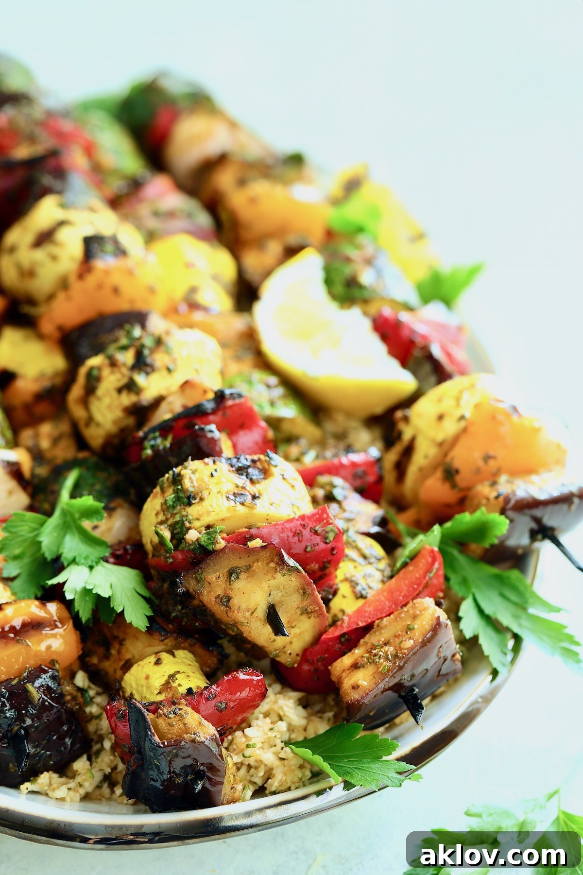 Platter of grilled vegetable kabobs adorned with fresh parsley and lemon slices, ready to be served.