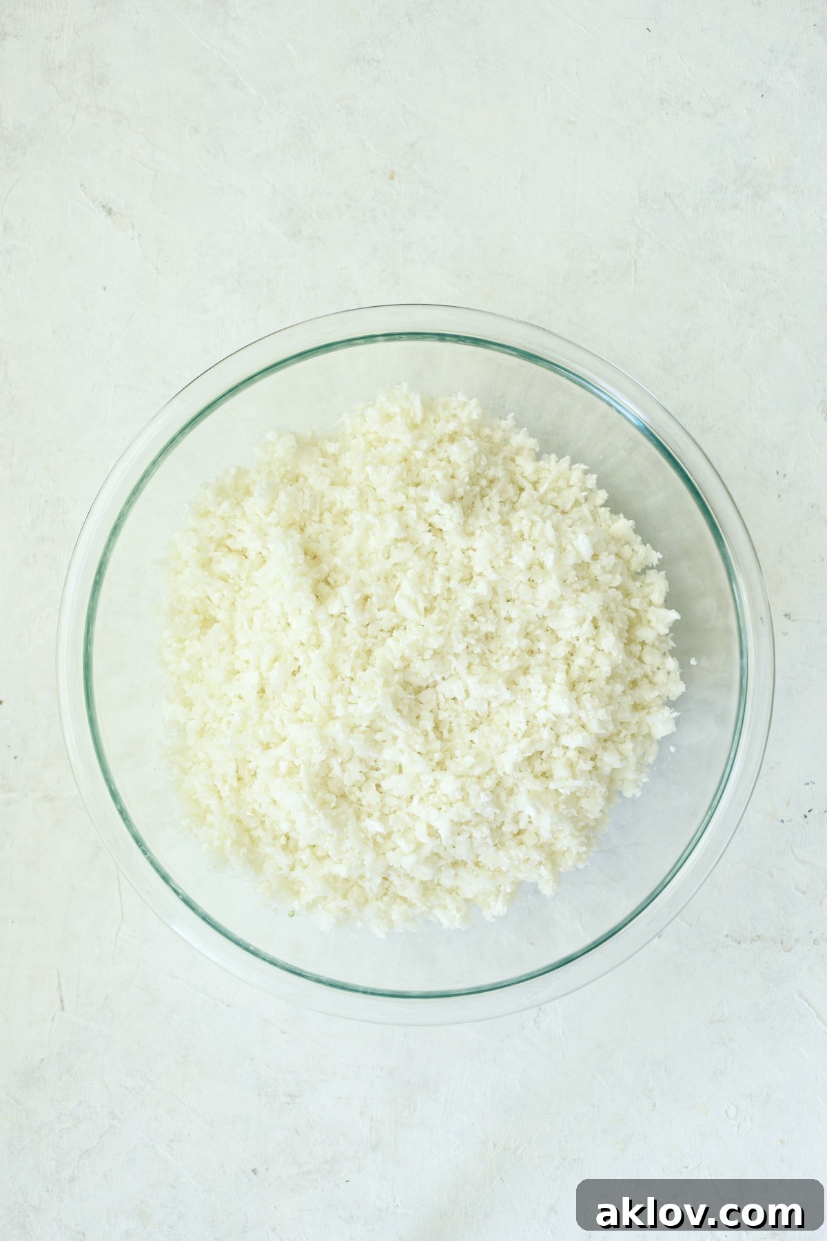 A bowl of finely grated cauliflower, prepared to resemble light and fluffy couscous, ready for marination.