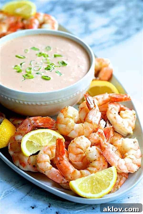 Close-up photo of Shrimp Cocktail Louis on white platter with sauce garnished with lemon wedges.