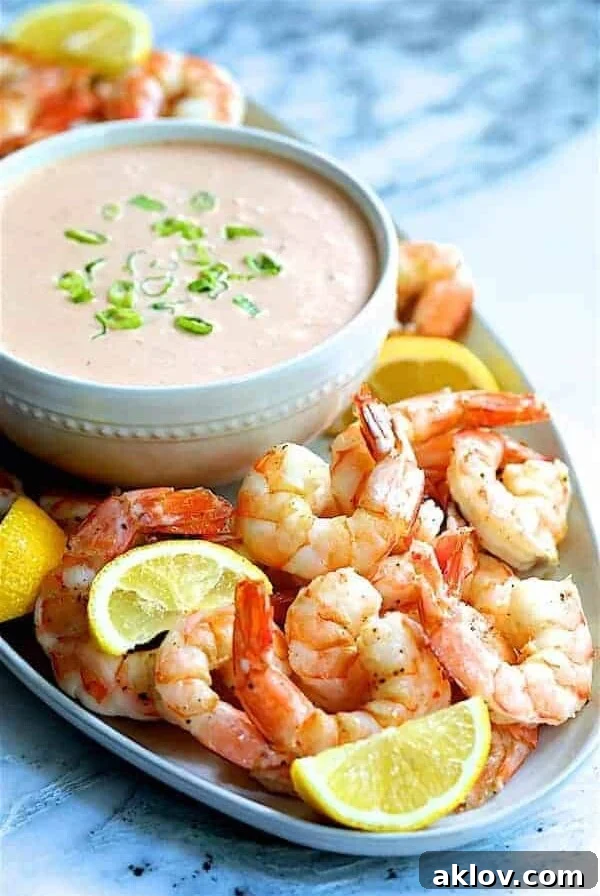 Shrimp Cocktail Louis on white platter with sauce garnished with lemon wedges.