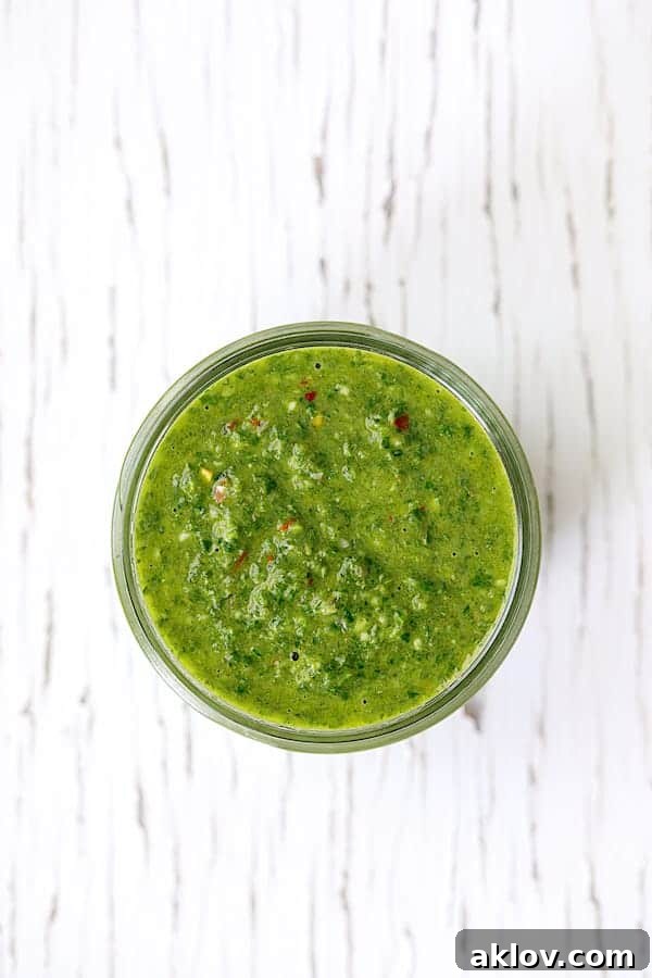 Photo of Purslane Chimichurri in a glass jar, ready to be served, on a white background.