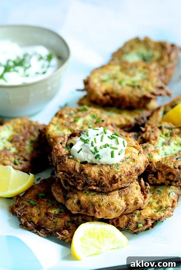 Zucchini Ricotta Fritters with yogurt chive topping garnished with lemon slices.