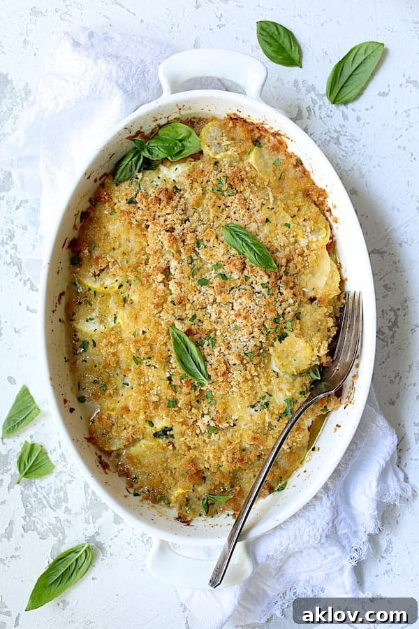 Photo of Yellow Squash and Tomato Gratin with Two Cheeses on white distressed background with white towel garnished with fresh basil.