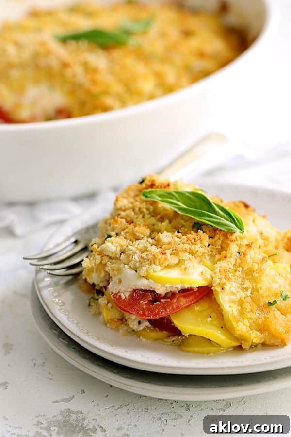 Close-up photo of a serving of Yellow Squash and Tomato Gratin with Two Cheeses on white plate.