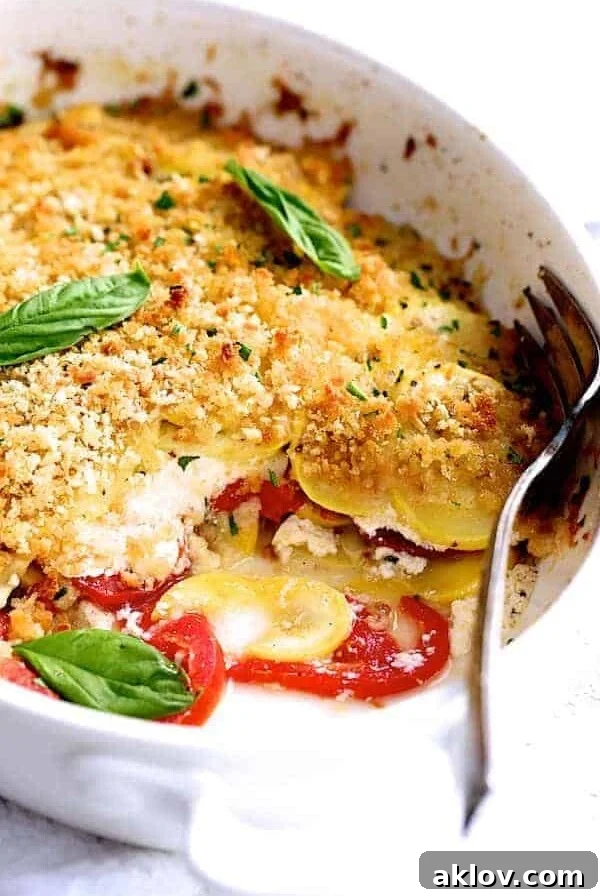 Yellow Squash and Tomato Gratin in oval white baking dish with piece removed.