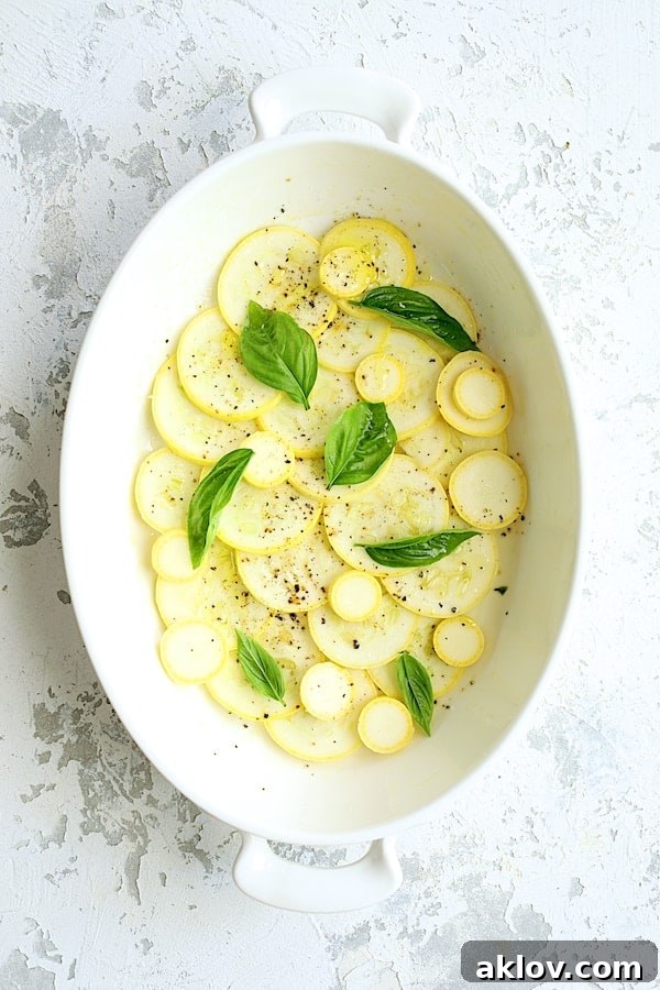 Photo of the first layer of yellow squash in white gratin dish.