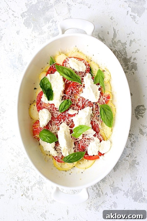 Photo after a layer of cheese and basil are added over tomato and yellow squash layers.