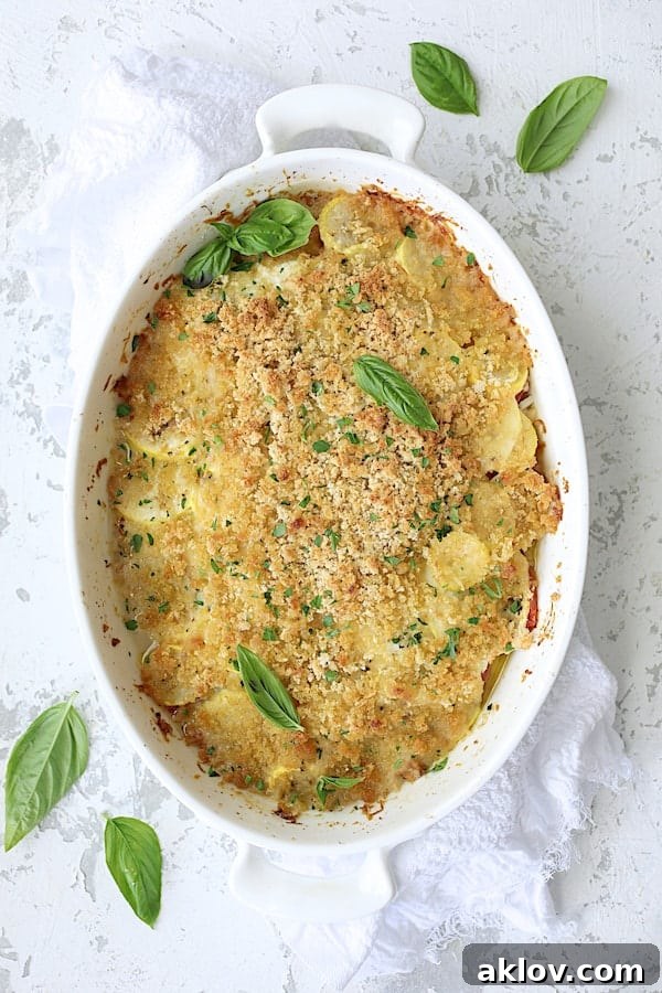 Photo of baked Yellow Squash and Tomato Gratin with Two Cheeses on white distressed background with white towel.