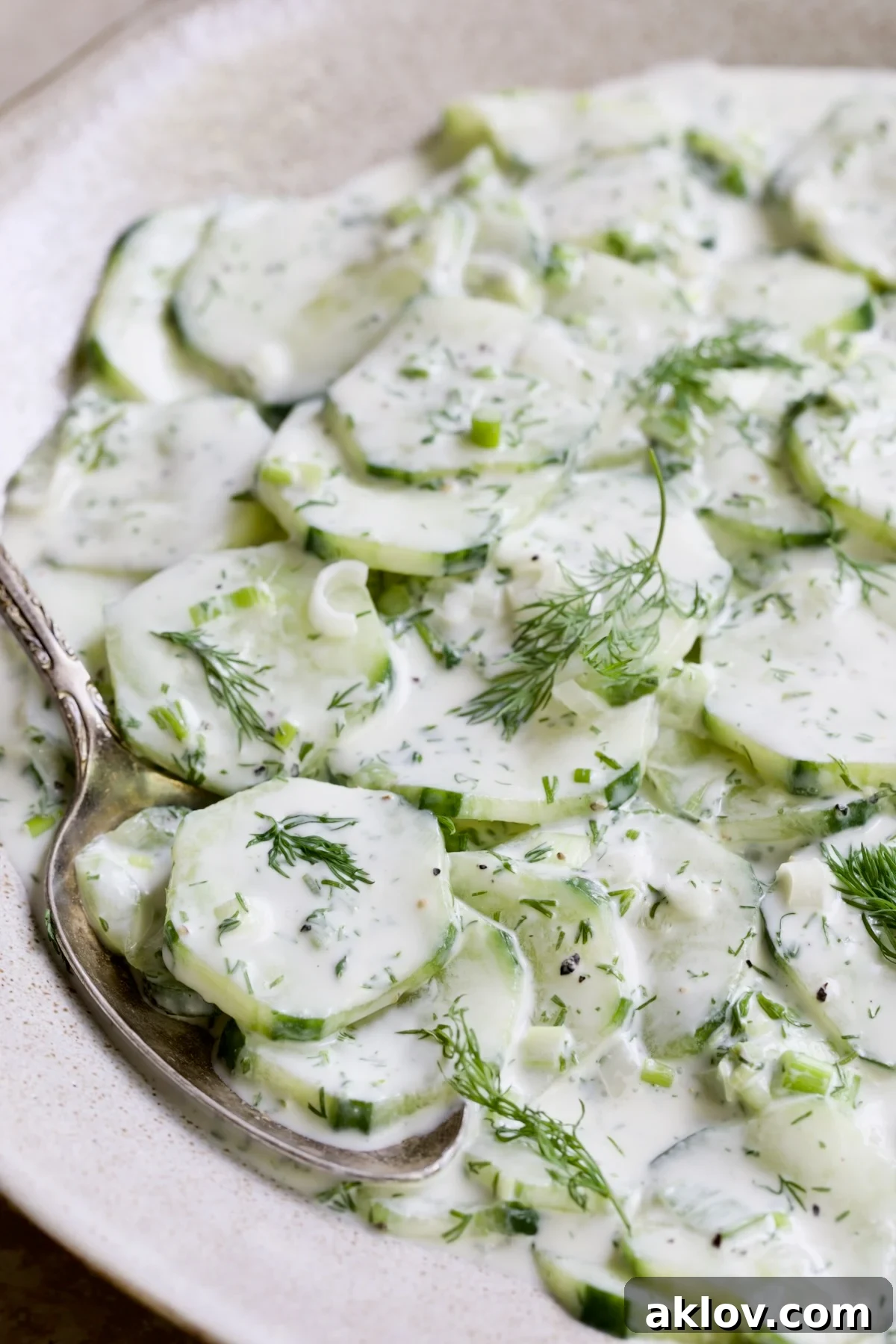 Yogurt Ranch Cucumber Salad in serving bowl with spoon lifting some out.