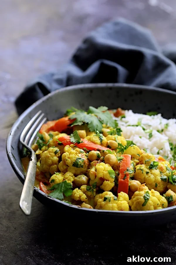 Golden Vegan Cauliflower Chickpea Curry 8 A perfectly portioned serving of Vegan Indian Cauliflower and Chickpea Curry in a elegant gray bowl, accompanied by basmati rice, ready to be enjoyed.