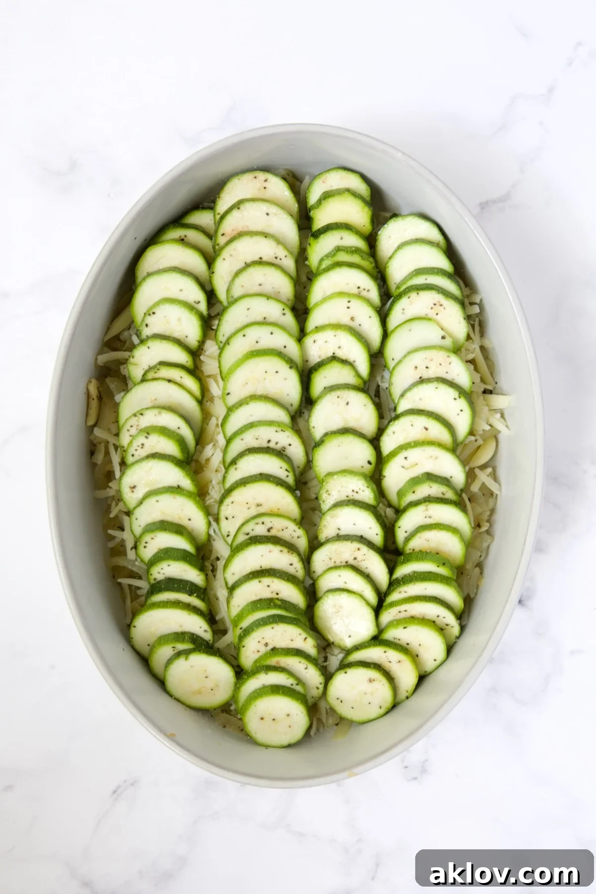 Layered zucchini slices placed over the cheese and onion mixture in the oval baking dish.