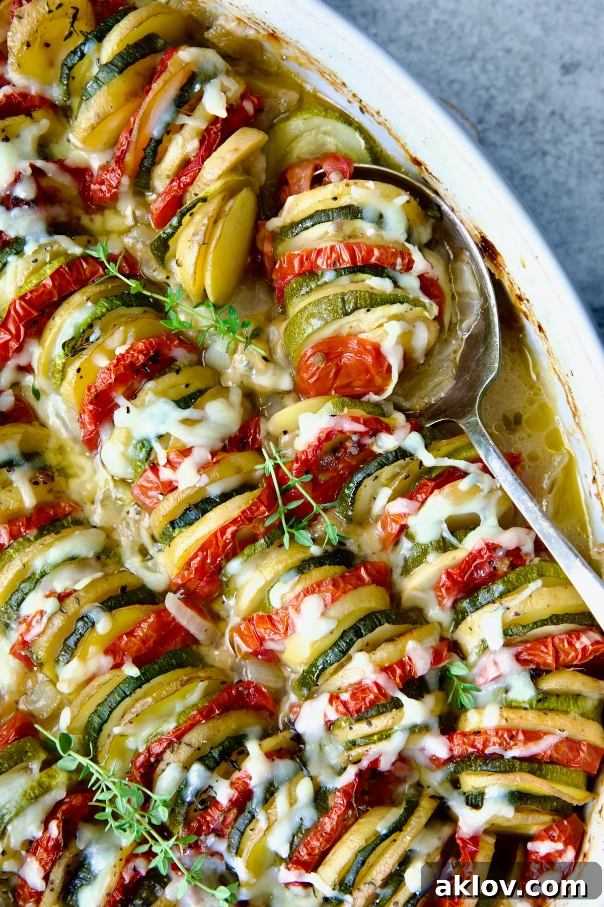 A freshly baked Vegetable Tian in an oval dish, ready to be served, with a serving spoon beside it.