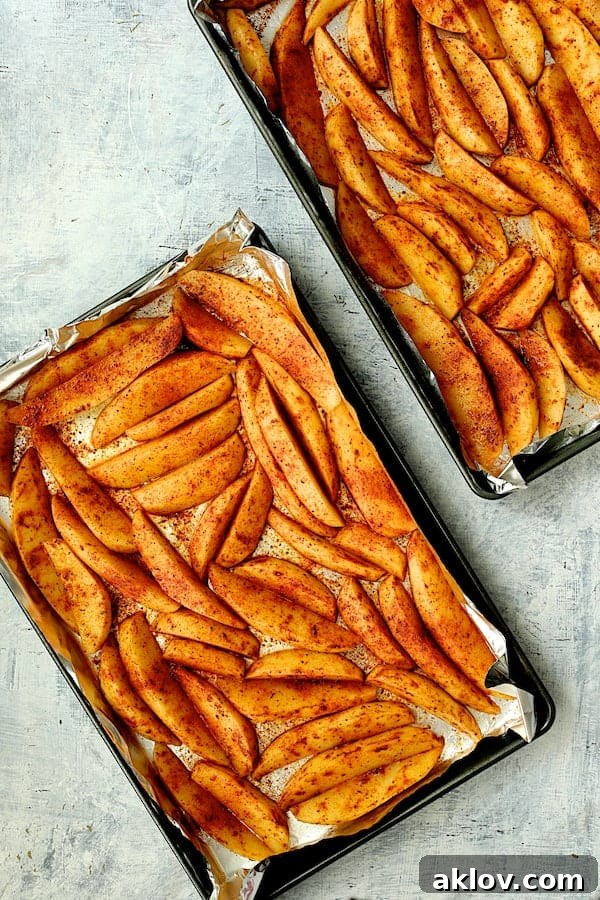 Crunchy Old Bay Wedges, Smothered in Vermont Cheddar 5 Two baking sheets filled with seasoned, uncooked potato wedges, arranged in a single layer, ready to be roasted in the oven.