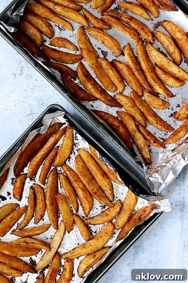 Crunchy Old Bay Wedges, Smothered in Vermont Cheddar 6 A close-up shot of two sheet pans laden with perfectly roasted potato wedges, showcasing their golden-brown color and crispy texture.