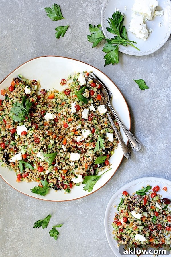 Mediterranean Farro Salad artfully presented on a white platter, with a portion served on a smaller individual white plate.